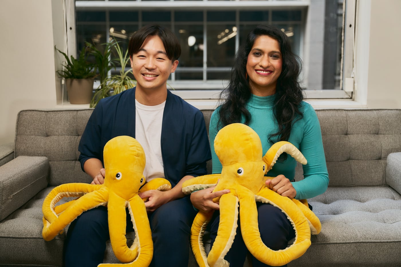 JustAI’s founders sitting together with yellow octopus plush toys